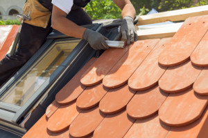 Ein Arbeiter tauscht Dachziegel auf einem Dach